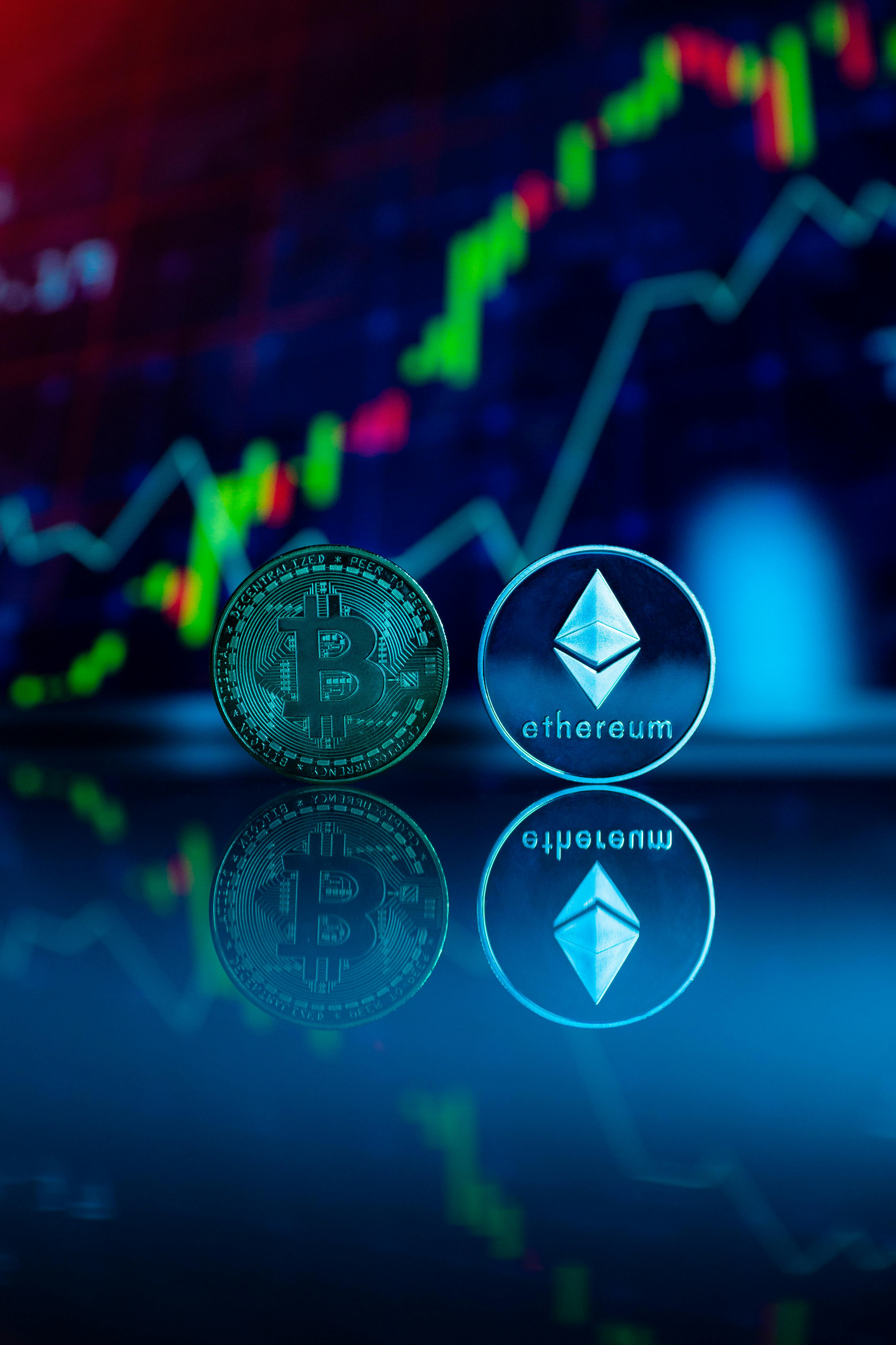 Bitcoin and Ethereum coins reflected on a glossy surface above a market chart